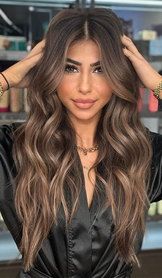 Woman with long, dimensional brunette balayage and voluminous waves, showcasing professional hair color at Silver Palm Salon in Littleton, CO