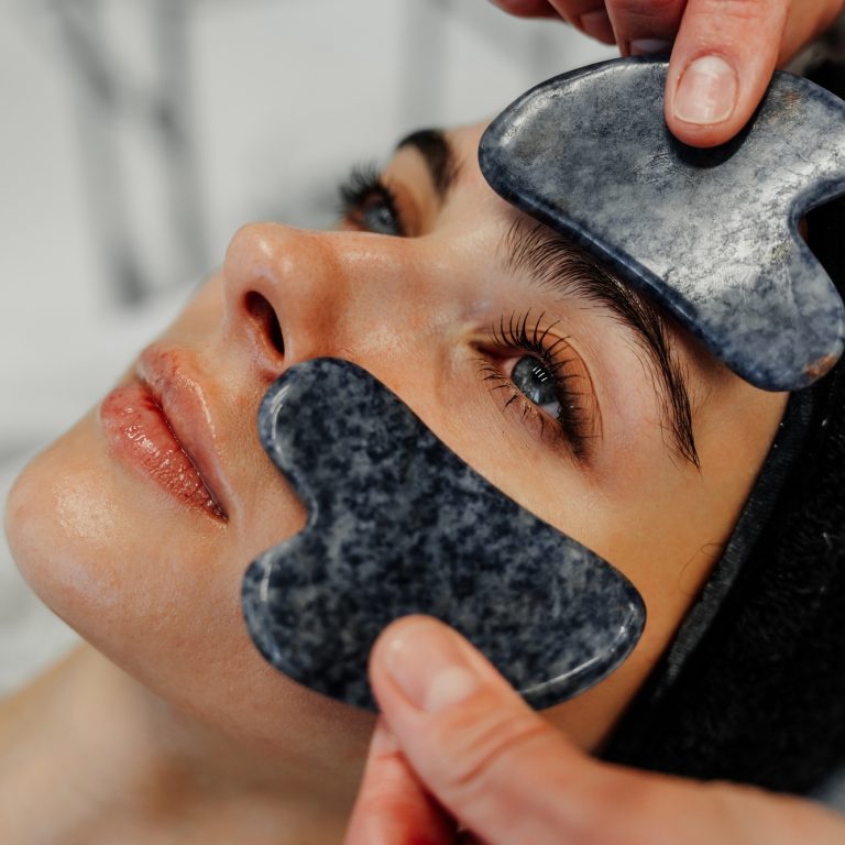 Relaxing facial treatment with gua sha stones at a spa during the day in a calm setting